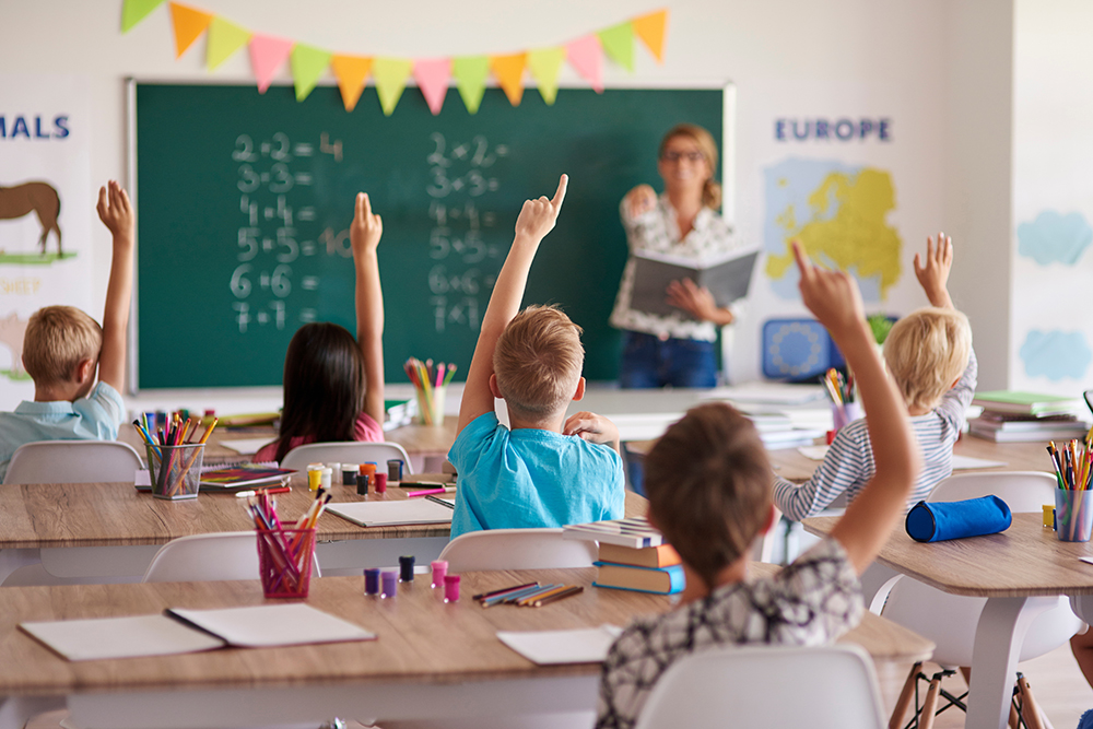 Students raising their hands in a classroom