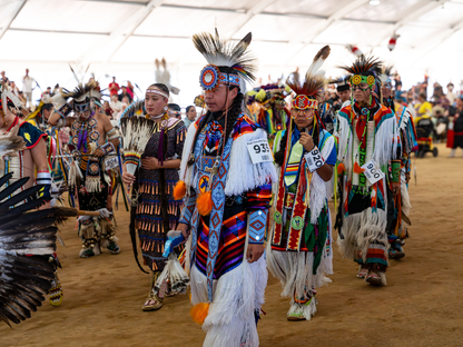 Native American dancers in colorful traditional attire at a vibrant pow wow gathering.