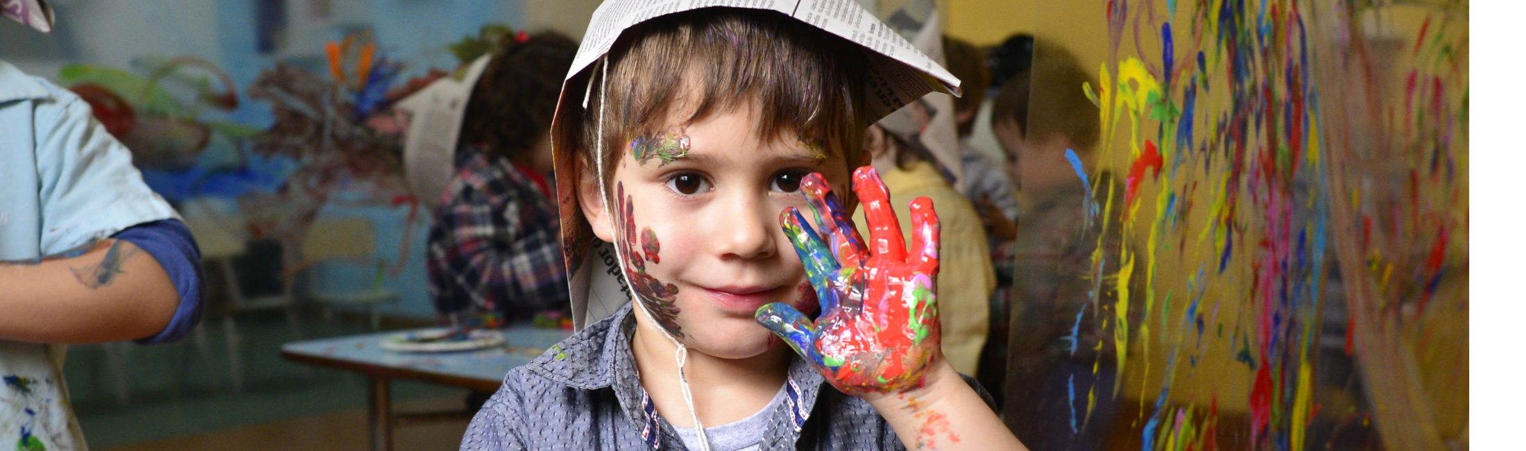 A joyful child with painted hands participates in a vibrant art class, expressing creativity and fun.