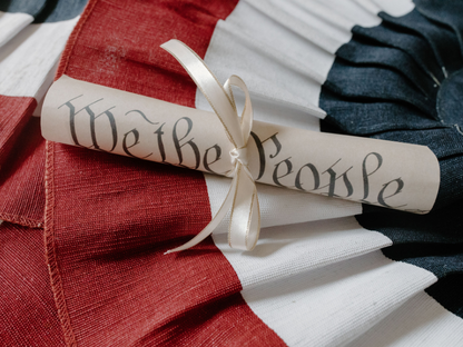 Close-up of a 'We the People' scroll on an American flag cloth background