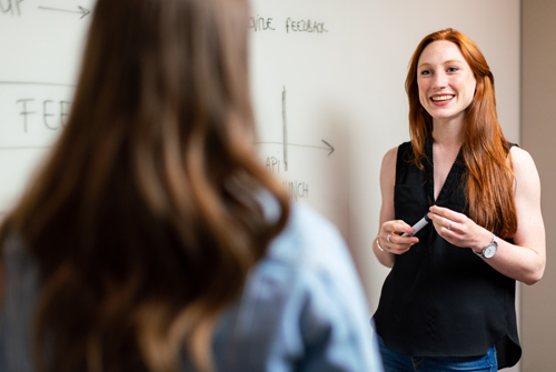 Young lady presenting at a whiteboard.