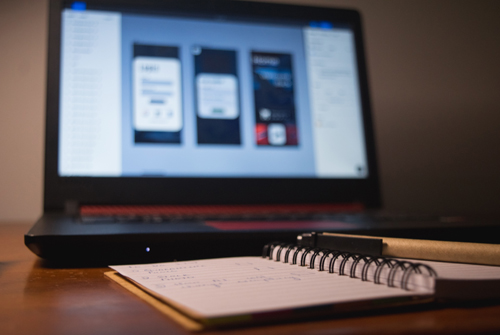 A notebook with a laptop in the background.