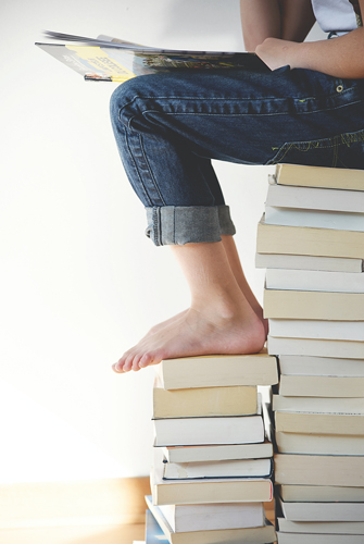 a person sitting on a stack of books reading